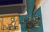 macro image of the tiny electronic component inside a mobile phone compared to the tip of a pencil for scale