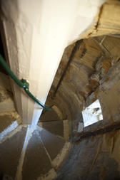 Overhead view looking down upon the stone treads of a spiral staircase inside the tower of an old building as they curve around the central support