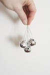 Silver Christmas bells dangling on threads from a mans fingers over a white background with copyspace for your seasonal greeting