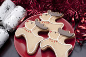 Reindeer Christmas biscuits with chocolate antlers, red noses and collars served on a festive table with crackers and decorations
