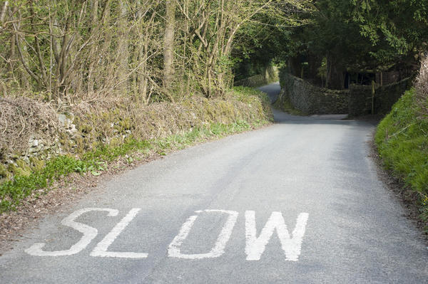 Painted caution on a small country road to slow down as the road approaches a bend