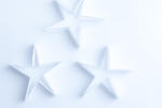 Delicate fragile paper stars on a white background for an ethereal spiritual Christmas background